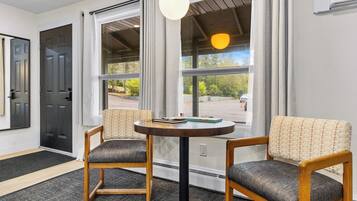 A room with two chairs, a table, and a window with a view of a parking lot.
