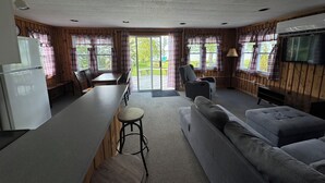 A compact living space with a kitchenette, a sofa, a dining table, and a TV.