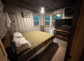 A small, single-bed room with a wooden headboard, a bedside table, a chair, and a window. - Stone Mountain Off Wolf Pen Gap Trails, Industrial Design 2 Bedroom 2 Bath Cabin (Mena)