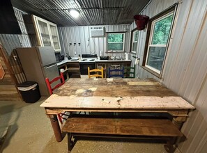 Eine rustikale Küche mit Holztisch, Stühlen und einem Kühlschrank.