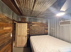 Ein Zimmer mit Holztür, einem Bett mit Steppdecke und einem Deckenventilator.