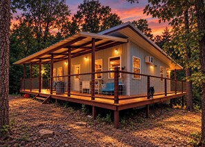 Eine Holzhütte mit überdachter Veranda, mehreren Fenstern und einem Holgitter.
