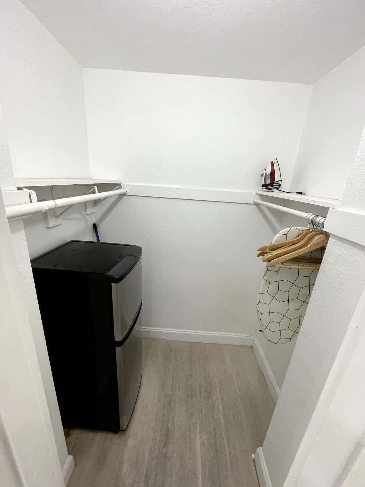 A laundry room with a washing machine, a drying rack, and a utility shelf.