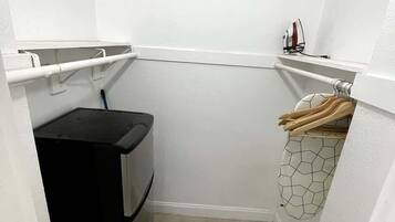 A laundry room with a washing machine, a drying rack, and a utility shelf.