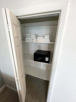 A closet with shelves containing folded towels and a black electronic device. - Shine Suites Balcony Studio (Miami)