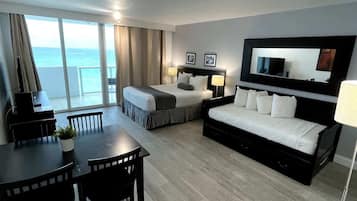 A hotel room with a bed, a desk, a chair, a dining table, and a large window with a view.