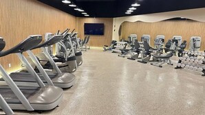 A gym with treadmills, weight machines, and dumbbells. - Shine Suites Balcony Studio (Miami)