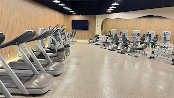 A gym with treadmills, weight machines, and dumbbells.