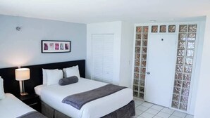 Ein Hotelzimmer mit Bett, Nachttisch, Lampe und einer Tür mit satinierten Glasscheiben.