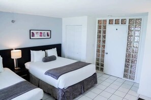 Ein Hotelzimmer mit Bett, Nachttisch, Lampe und einer Tür mit satinierten Glasscheiben.