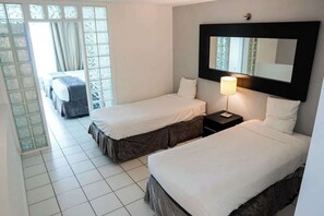 A hotel room with two beds, a large mirror, a nightstand with a lamp, and a view through a glass door. - Shine Suites Balcony Duplex (Miami Beach)