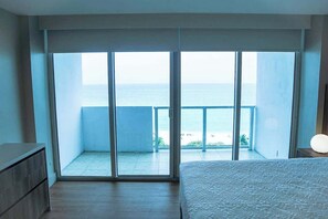 A bedroom with a large sliding glass door leading to a balcony with a view of the sea. - Shine Suites Balcony Studio (Miami Beach)