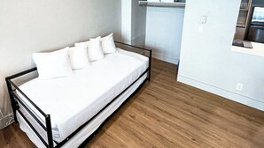 A modern bedroom with a bed, wooden flooring, a built-in wardrobe, and a small kitchenette. - Shine Suites Balcony Studio (Miami Beach)