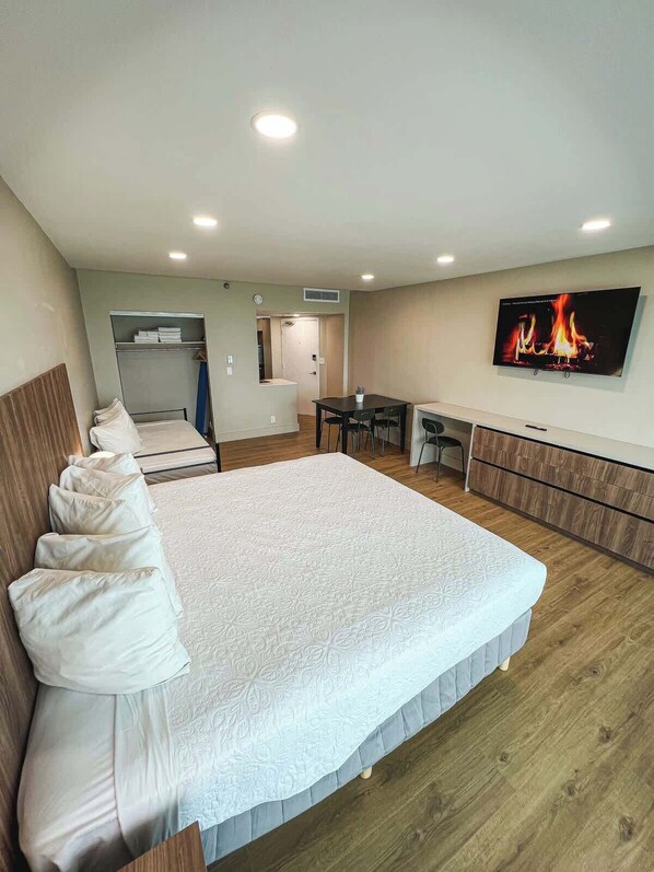 A hotel room with a large bed, a desk, a TV, and a fireplace. - Shine Suites Balcony Studio (Miami Beach)