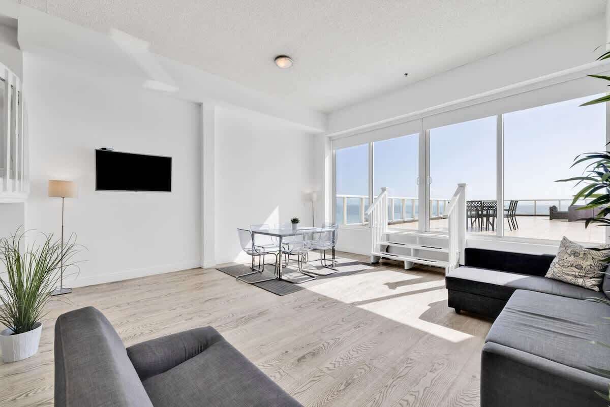 A spacious living area with a large window, a flat-screen TV, and a seating arrangement.