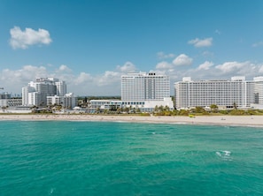 Eine Küstenstadt mit Hochhäusern, einem Strand und klarem türkisblauem Wasser.