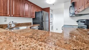 A kitchen with granite countertops, stainless steel appliances, and wooden cabinets. - Shine Suites Balcony Duplex (Miami Beach)