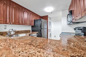 A kitchen with granite countertops, stainless steel appliances, and wooden cabinets. - Shine Suites Balcony Duplex (Miami Beach)