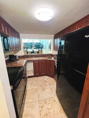 A kitchen with a black refrigerator, wooden cabinets, a microwave, and a coffee maker. - Shine Suites Balcony Duplex (Miami Beach)