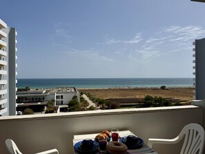 A balcony with a table set for breakfast overlooking a beach and ocean. - Alvor Tower & SEA View by Homing (Portimão)