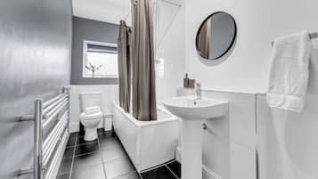 A modern bathroom with a toilet, bathtub, and sink.