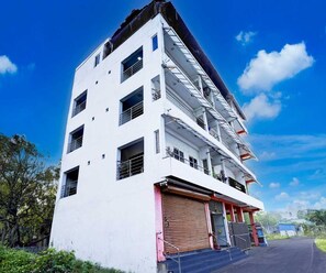 A multi-story building with a white facade, multiple balconies, and a red garage door. - Townhouse R S Puram Junction (Coimbatore)