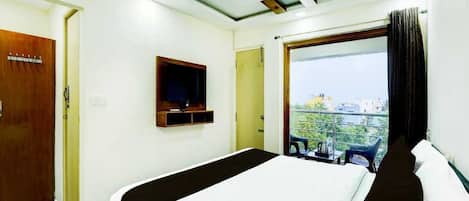 A hotel room with a bed, a television, a ceiling fan, and a window with a view.