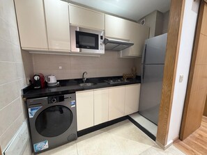 A compact kitchen with a washing machine, microwave, and refrigerator. - An oasis in Guéliz with a free pool and free parking (Marrakesh)