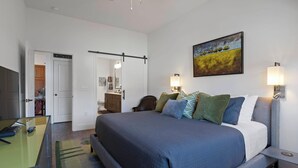 Ein Hotelzimmer mit einem Bett, Nachttischlampen, einem Schreibtisch und einem Gemälde an der Wand.