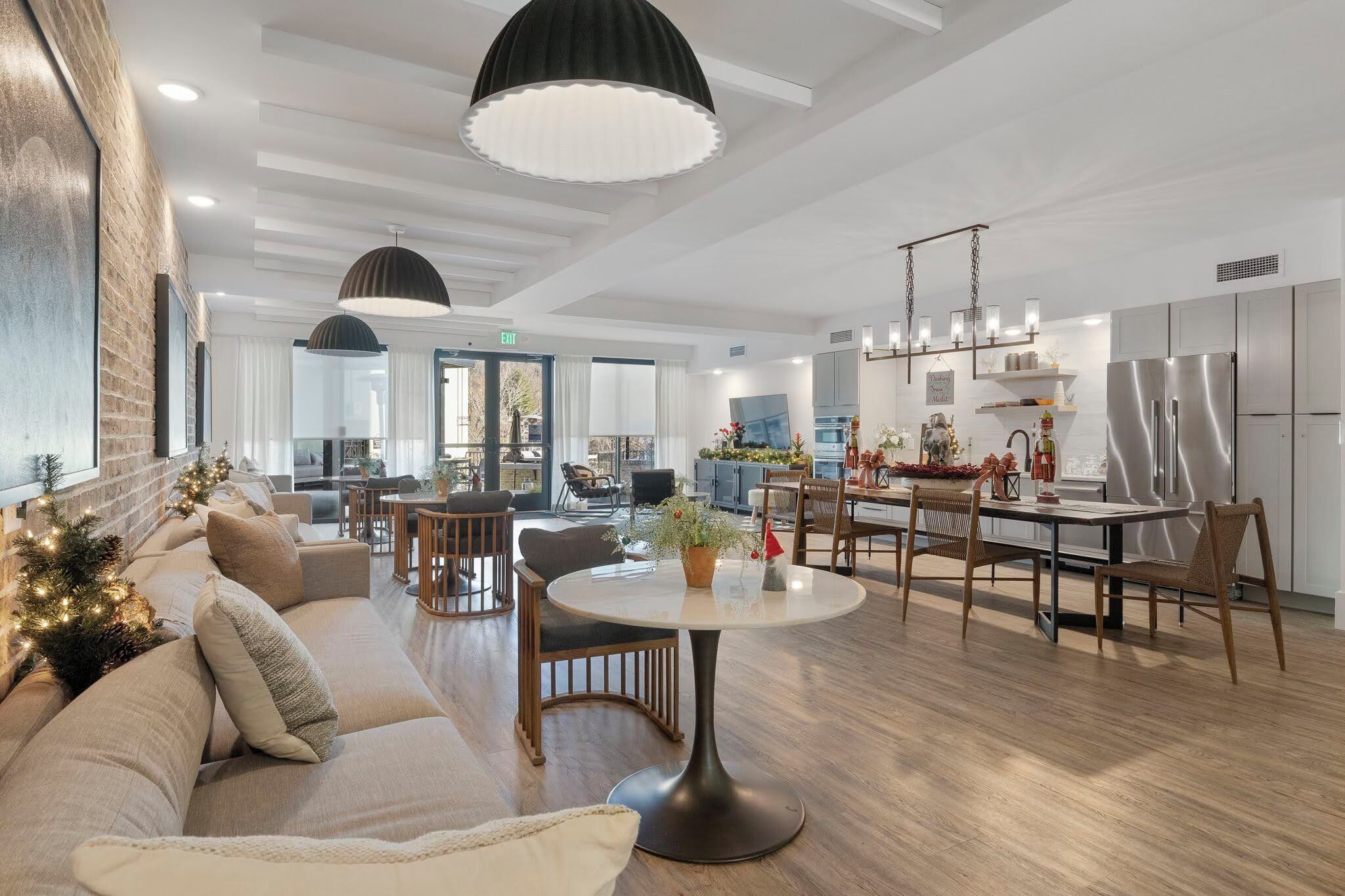 Una sala de estar moderna con un sofá, una mesa de comedor redonda y una zona de cocina con refrigerador y armarios.