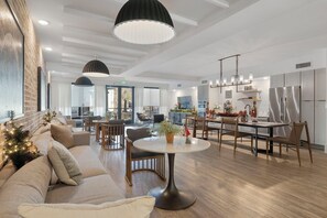 Een moderne woonkamer met een bank, een ronde eettafel en een keuken met een koelkast en kasten.