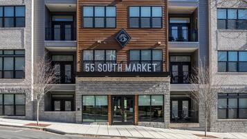 En byggnad med flera våningar, ett stort och väl synligt skylt med texten ”55 SOUTH MARKET”, stora fönster och en fasad av sten.