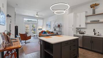 Une cuisine moderne dotée d’un îlot central, de meubles blancs et d’un four encastré.