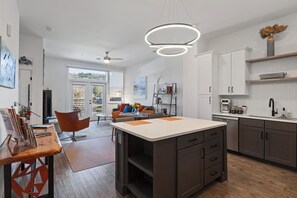 Uma cozinha moderna com ilha central, armários brancos e forno embutido.