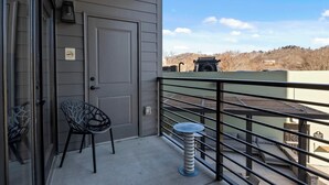 Ein Balkon mit Tür, einem Stuhl, einem kleinen Tisch und einem Geländer.