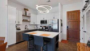 A modern kitchen with white cabinets, stainless steel appliances, and a central island with bar stools.