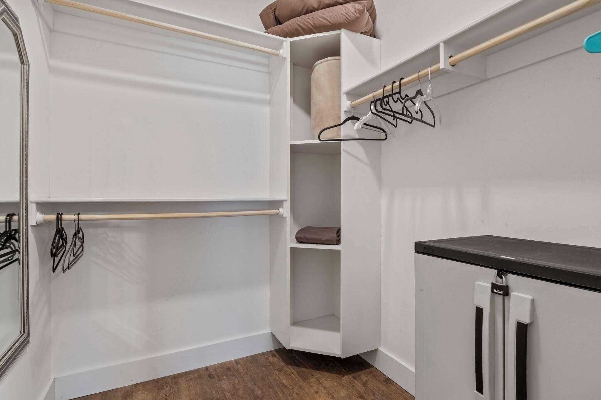 Ein begehbarer Kleiderschrank mit Spiegel, Regalen und Kleiderstange.