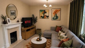 Ein Wohnzimmer mit Kamin, einer Couch, einem Couchtisch und Kunstwerken an den Wänden.