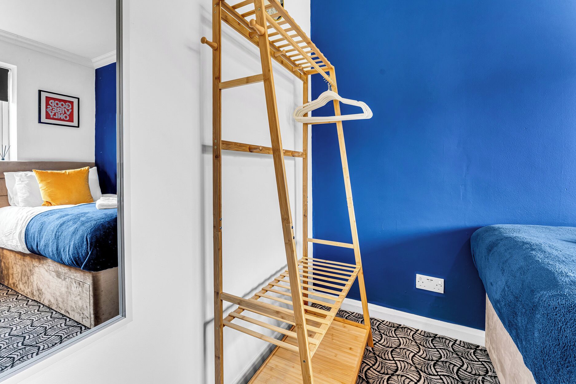 A room with a bunk bed, a wooden ladder, a mirror, and a blue wall.