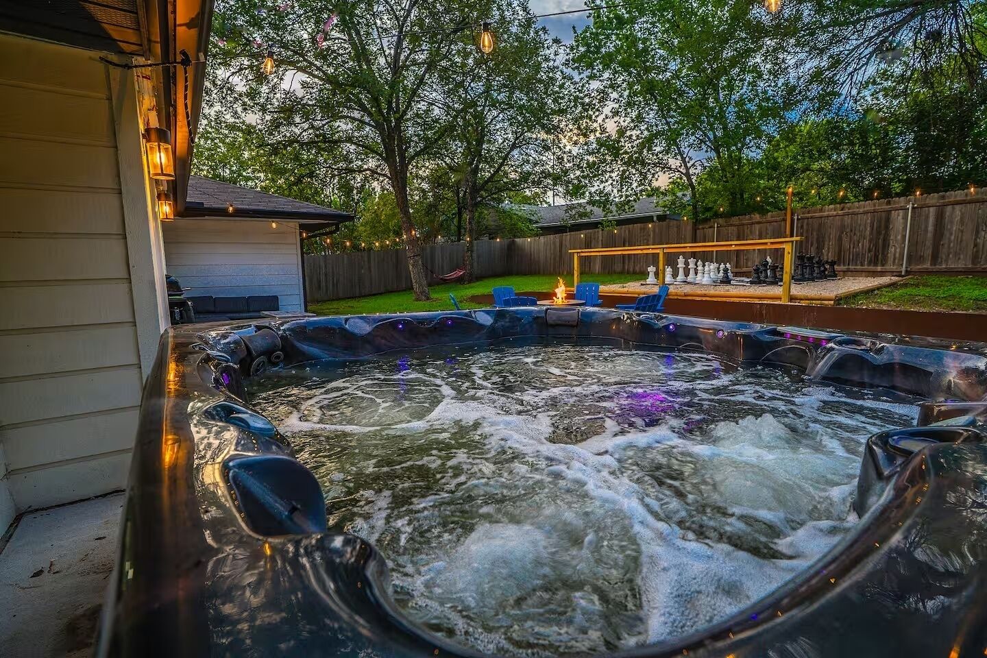 A hot tub with a wooden deck and a chess table in the background.