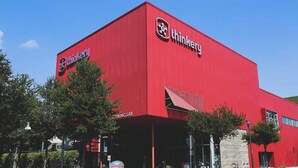 A red building with the 'thinkery' logo and a sign indicating a 'WARNING LAB'.