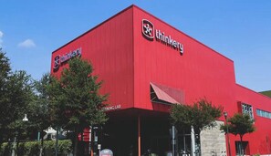 A red building with the 'thinkery' logo and a sign indicating a 'WARNING LAB'.