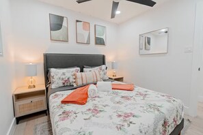 A bedroom with a bed, nightstands, lamps, and artwork on the walls.
