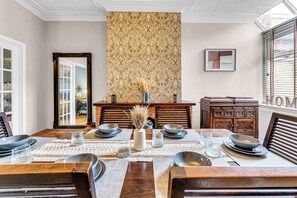A dining room with a high ceiling, a patterned wallpaper, a fireplace, and a view of the outside through a window. - Stoke Townhouse (Stoke-on-Trent)
