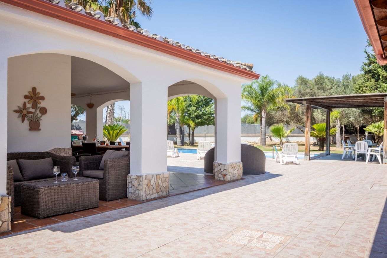 An outdoor patio with a pool, seating area, and covered structures.