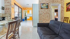 A living room with a sofa and dining area with chairs and a table set for a meal.