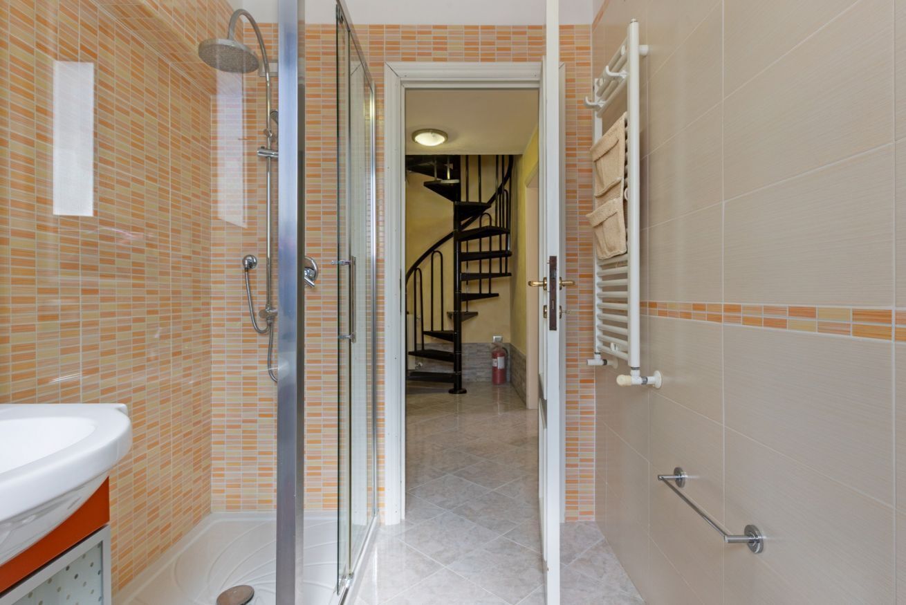 A bathroom with a shower, a sink, and a tiled floor.
