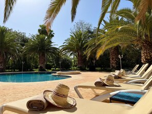 A poolside area with lounge chairs and a hat on one of them. - Villa Amazura 6 Bedroom With Private Pool (Marrakech)