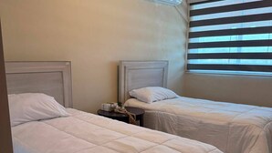 A hotel room with two beds, a ceiling fan, and a window with blinds. - Deluxe Unique 2BR/2BA Apartment – Stylish, Modern at San Cristobal City, DR. (San Cristóbal)