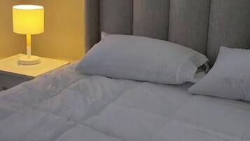 Uma cama com cabeceira, abajur e almofadas.